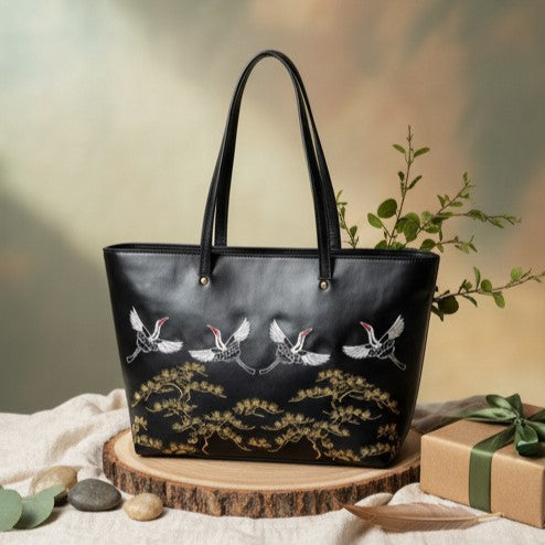 Antheia black embroidered plant-based leather tote bag displayed on wooden stand with plant and gift box, ideal for premium gifting and everyday luxury use