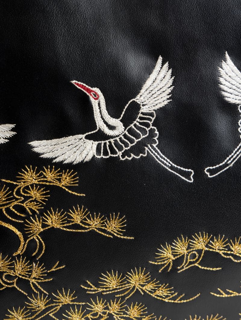 Close-up of intricate gold embroidery on black plant-based leather tote bag showcasing detailed craftsmanship and luxury finish