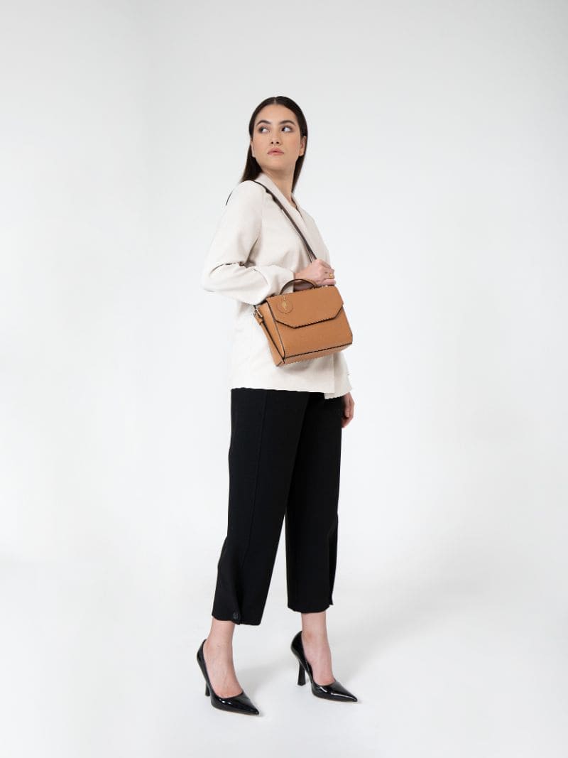 Model wearing Asteria caramel vegan leather crossbody bag with adjustable strap, styled for everyday elegant wear