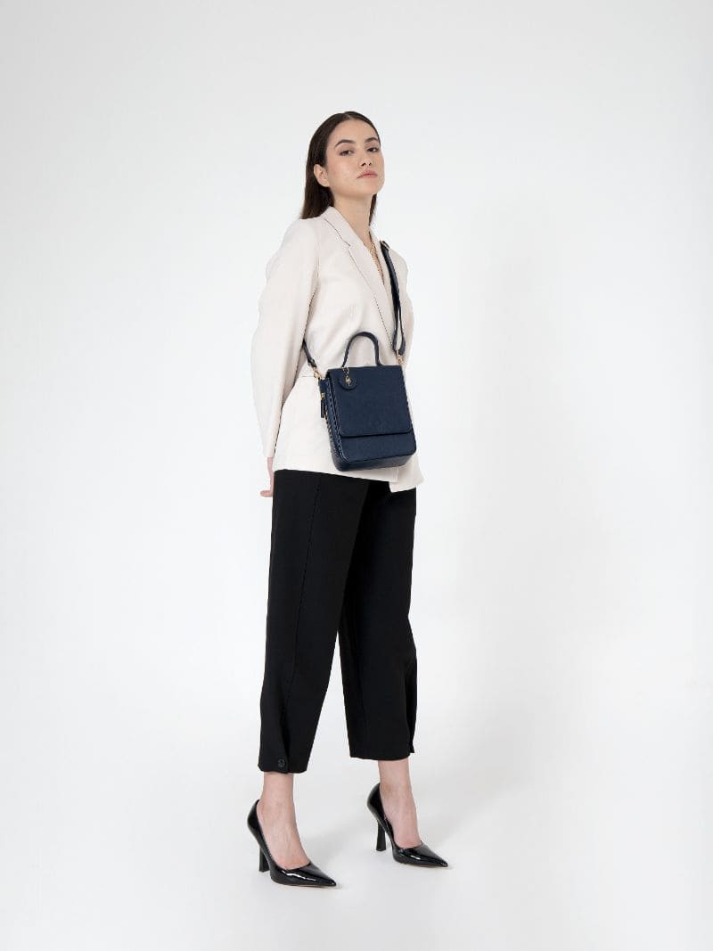 Model wearing Ceres navy blue plant-based leather crossbody bag with structured silhouette on a clean white background