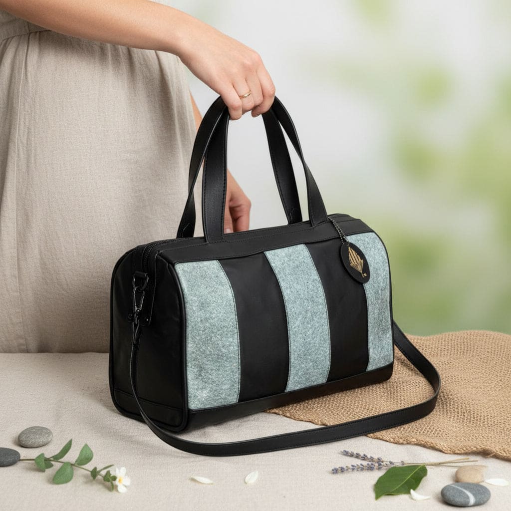 Person carrying the Chloris plant leather bowler bag in black and dark grey, handcrafted from cactus leather and Malai leather with a detachable shoulder strap.