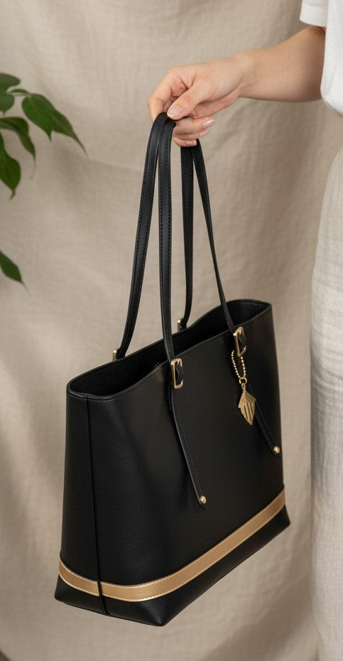 Minerva black plant leather tote bag showing handle design and gold detailing while being held
