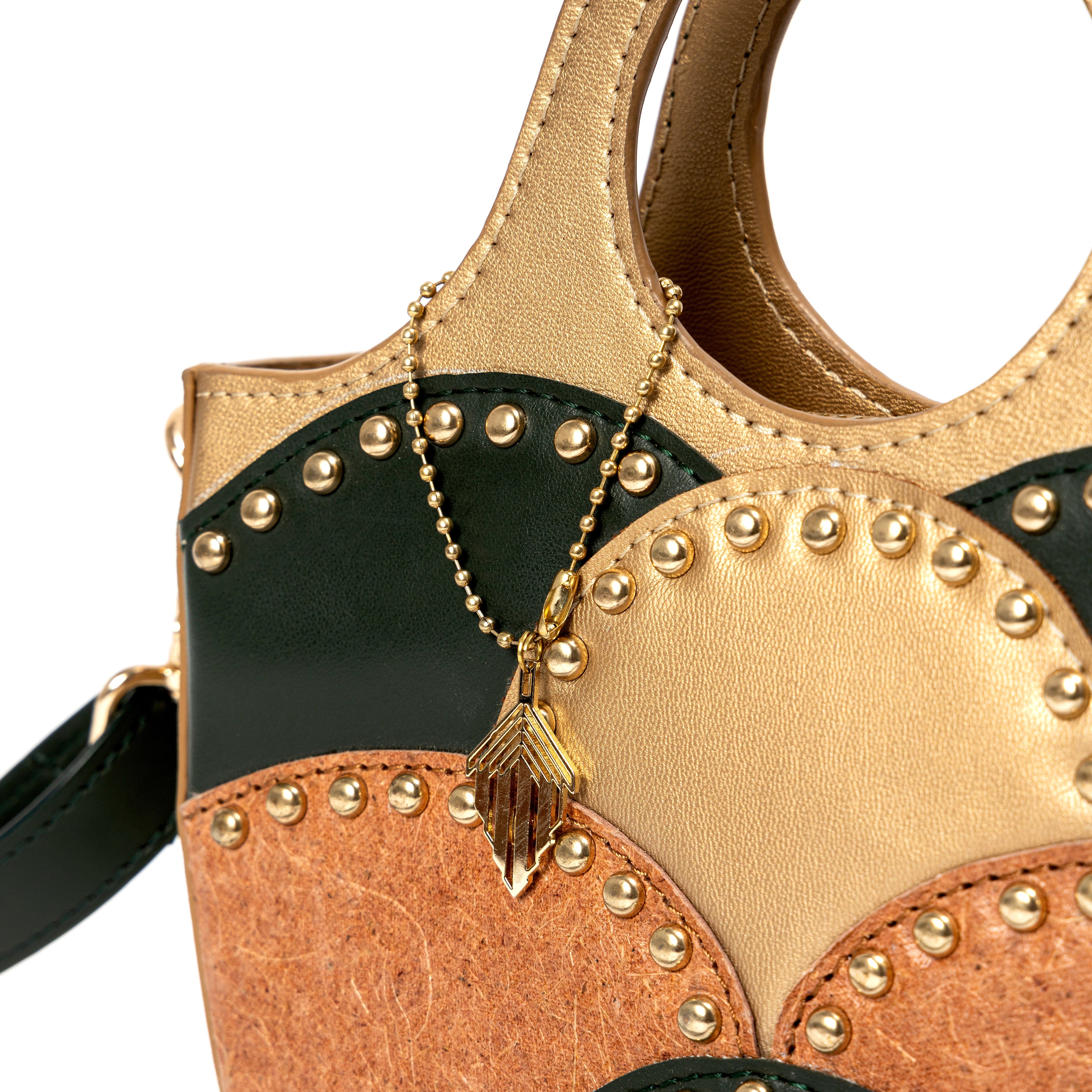 Close up detail of Savannah Gold plant leather sling bag showing textured panels and gold stud accents
