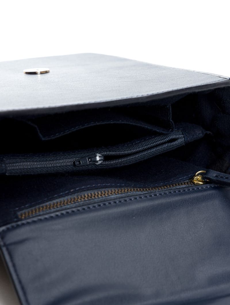 Interior view of Ceres navy blue plant-based leather crossbody bag showing compartments and zip pocket