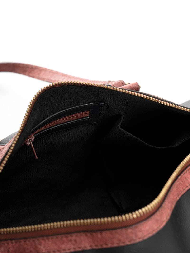 Interior view of the Salacia plant leather bowler bag in black and madder red, featuring a spacious compartment with zip and slip pockets, handcrafted from fairtrade canvas, cactus leather and malai leather.