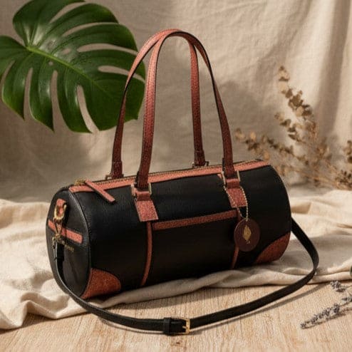 Salacia plant leather bowler bag in black and madder red with detachable shoulder strap, handcrafted from fairtrade canvas, cactus leather and malai leather in a lifestyle setting.