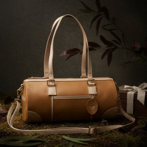 Front view of the Salacia plant leather bowler bag in caramel and almond, handcrafted from fairtrade canvas with plant-based apple leather trims and a detachable shoulder strap.