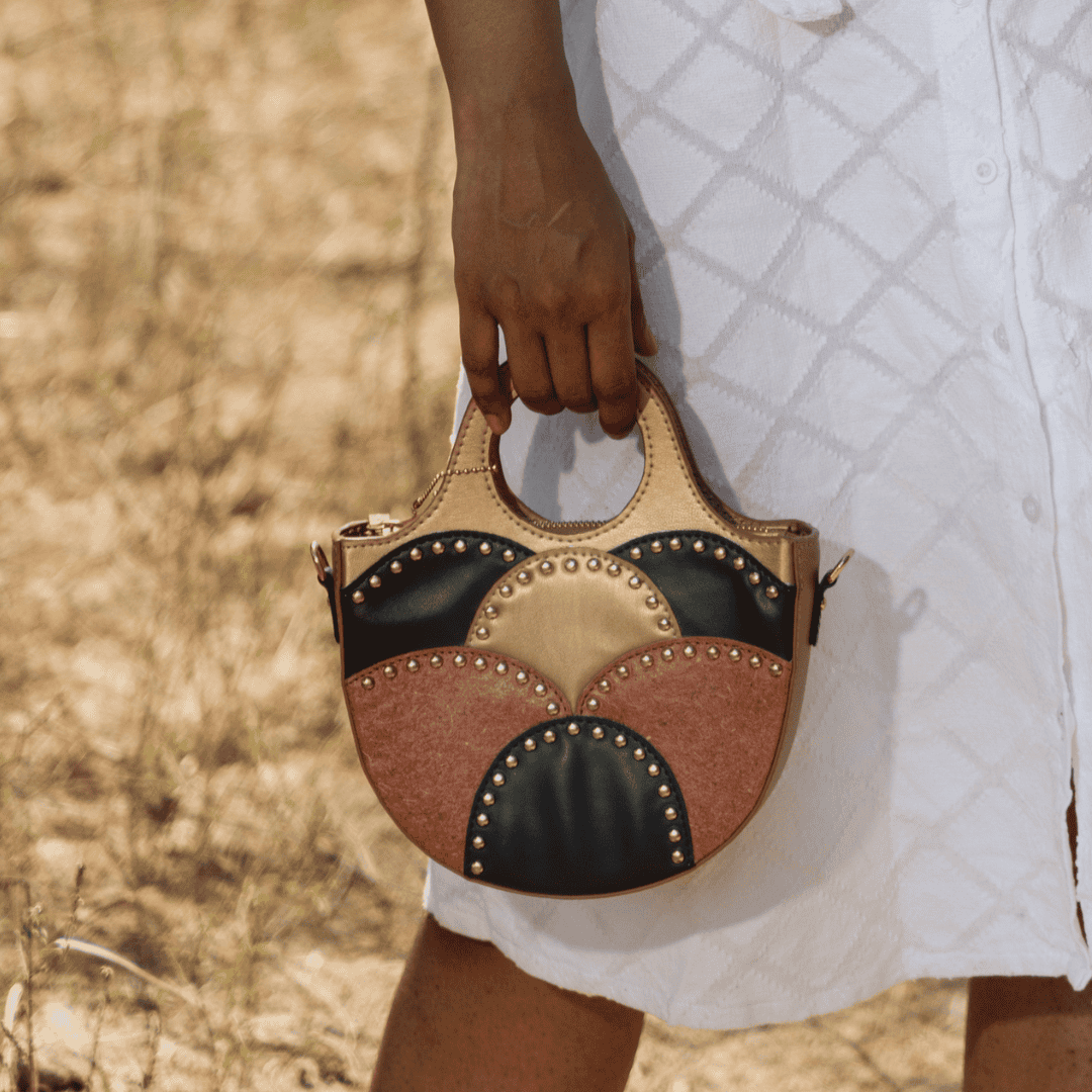 Hand carrying Savannah Gold plant leather sling bag in outdoor lifestyle setting