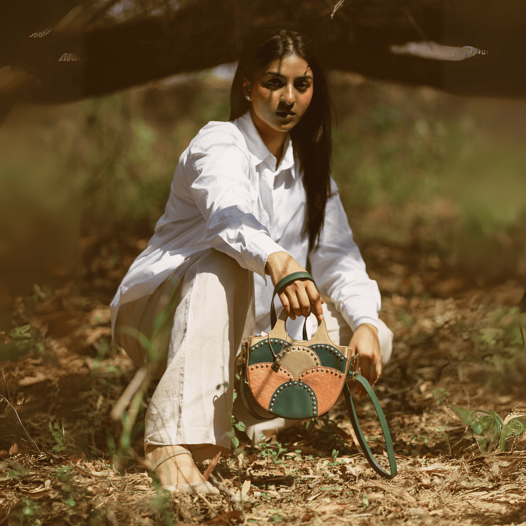 Model holding Savannah Gold plant leather sling bag outdoors in natural forest setting