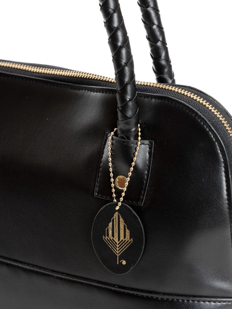 Close-up of Theia black vegan leather shoulder bag handle and logo tag highlighting craftsmanship, detailing and premium finish