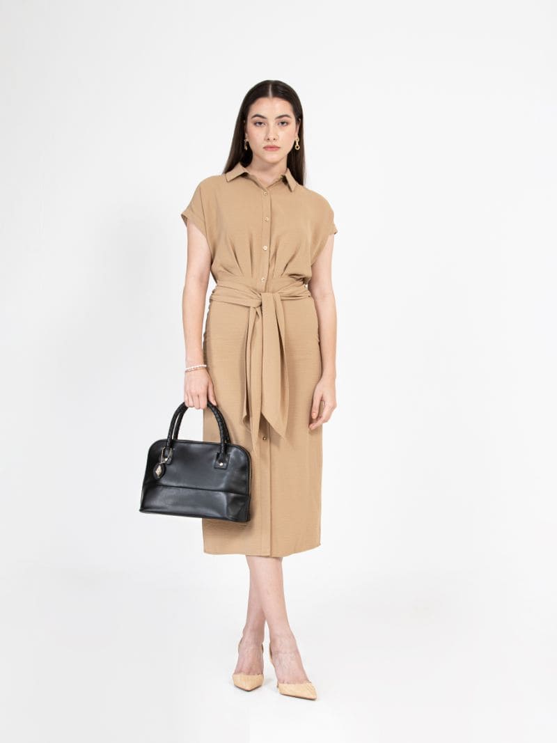 Model holding Theia black vegan leather shoulder bag paired with a neutral outfit, showcasing size, structure and everyday styling