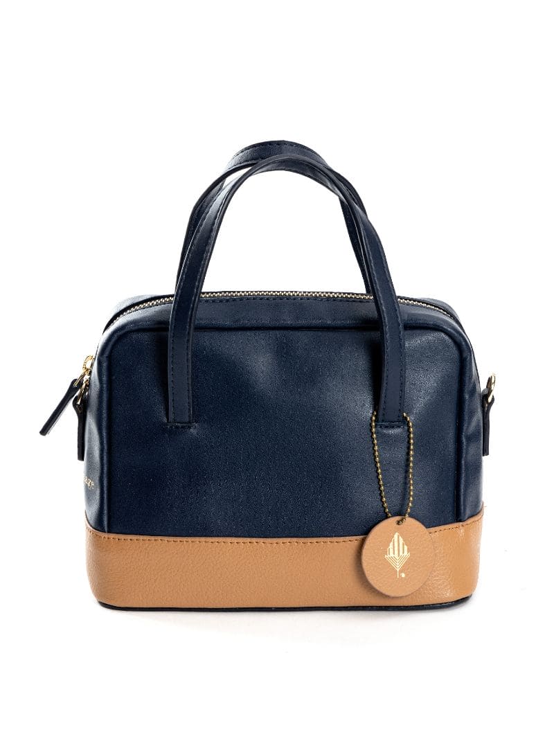 Clean front view of navy blue and caramel plant leather satchel crossbody bag on a plain background, highlighting minimalist design and signature charm detail